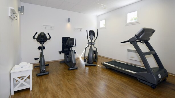 Ein Fitnessraum mit Laufband, Crosstrainern und einem stationären Fahrrad.