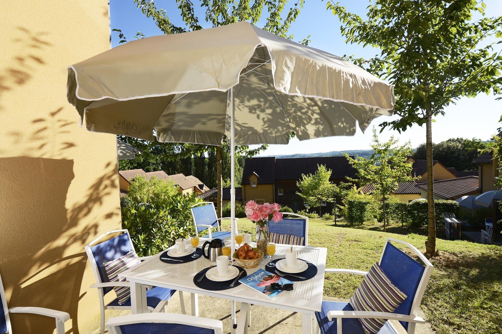 An outdoor dining area with a table, chairs, and an umbrella.