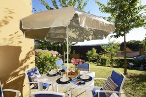 An outdoor dining area with a table, chairs, and an umbrella. - Holiday Home in Sarlat near Grottes de Lascaux (Sarlat La Caneda)
