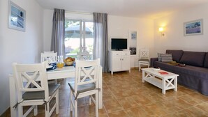 Ein Wohnzimmer mit Essbereich, Fernseher und Sofa.