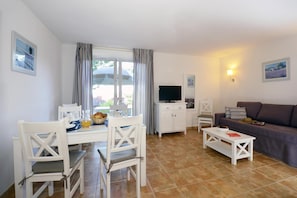 A living room with a dining area, a television, and a sofa. - Holiday Home in Sarlat near Grottes de Lascaux (Sarlat La Caneda)