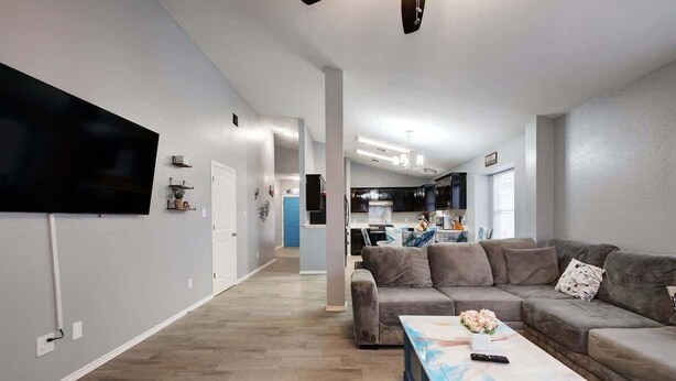 Ein modernes Wohnzimmer mit einem großen Flachbildfernseher, einem grauen Sofa und einem Couchtisch mit einer Blumenvase.