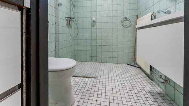 Um banheiro pequeno, com azulejos, incluindo vaso sanitário, chuveiro e janela.