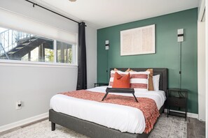 A bedroom with a bed, a window, a staircase, and a green wall. - [REFRESHED] Quiet & Quaint 1BR 5min to airport and 15mins to downtown (College Park)