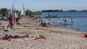Una playa con gente tomando el sol y nadando.