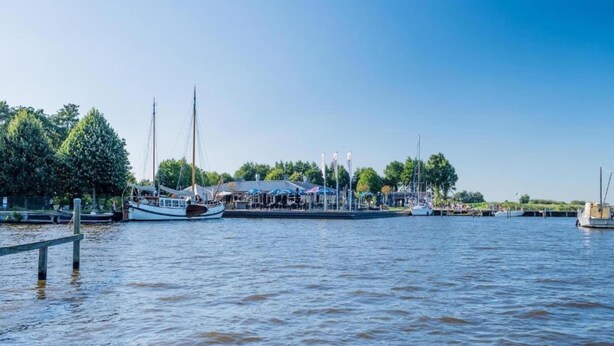 Zona costera con barcos amarrados, un muelle y un edificio con techo.