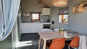 Cocina compacta con comedor, que incluye una mesa de madera, dos sillas y una lámpara colgante.