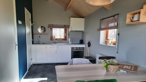Cocina pequeña con gabinetes blancos, un lavamanos y una ventana con persianas.