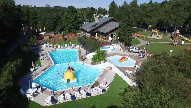 Vista aérea de un resort con varias piscinas, un tobogán acuático y un edificio grande con techo inclinado.
