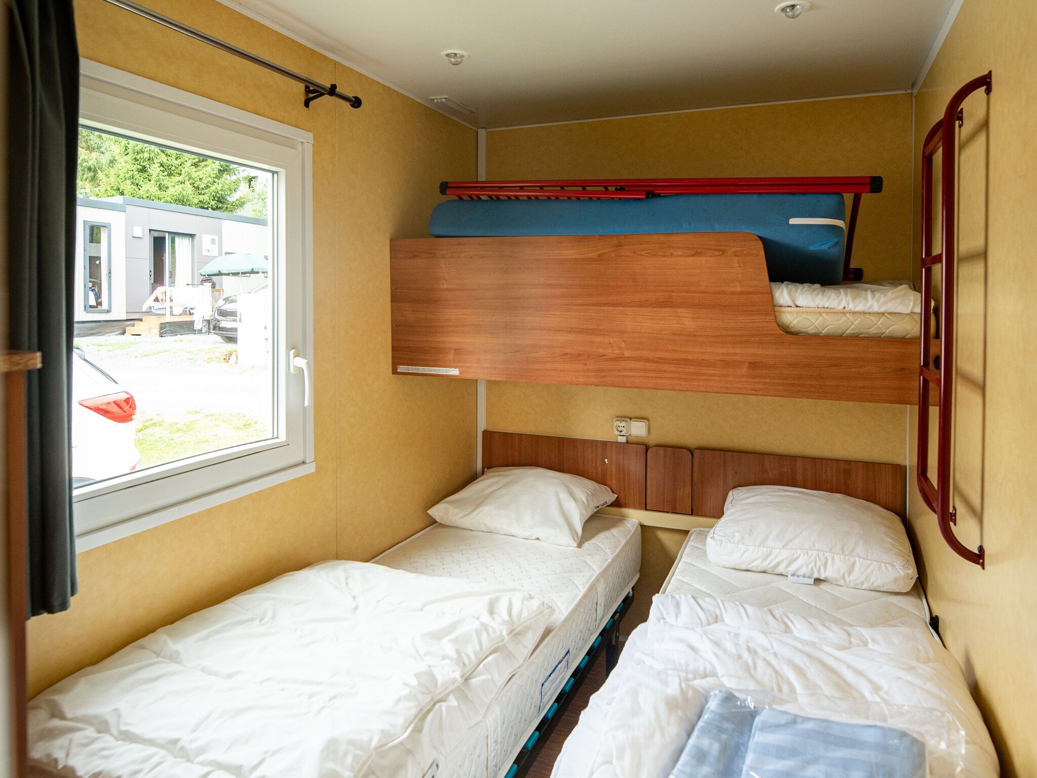 Ein kleines Zimmer mit Stockbetten und einem Fenster.