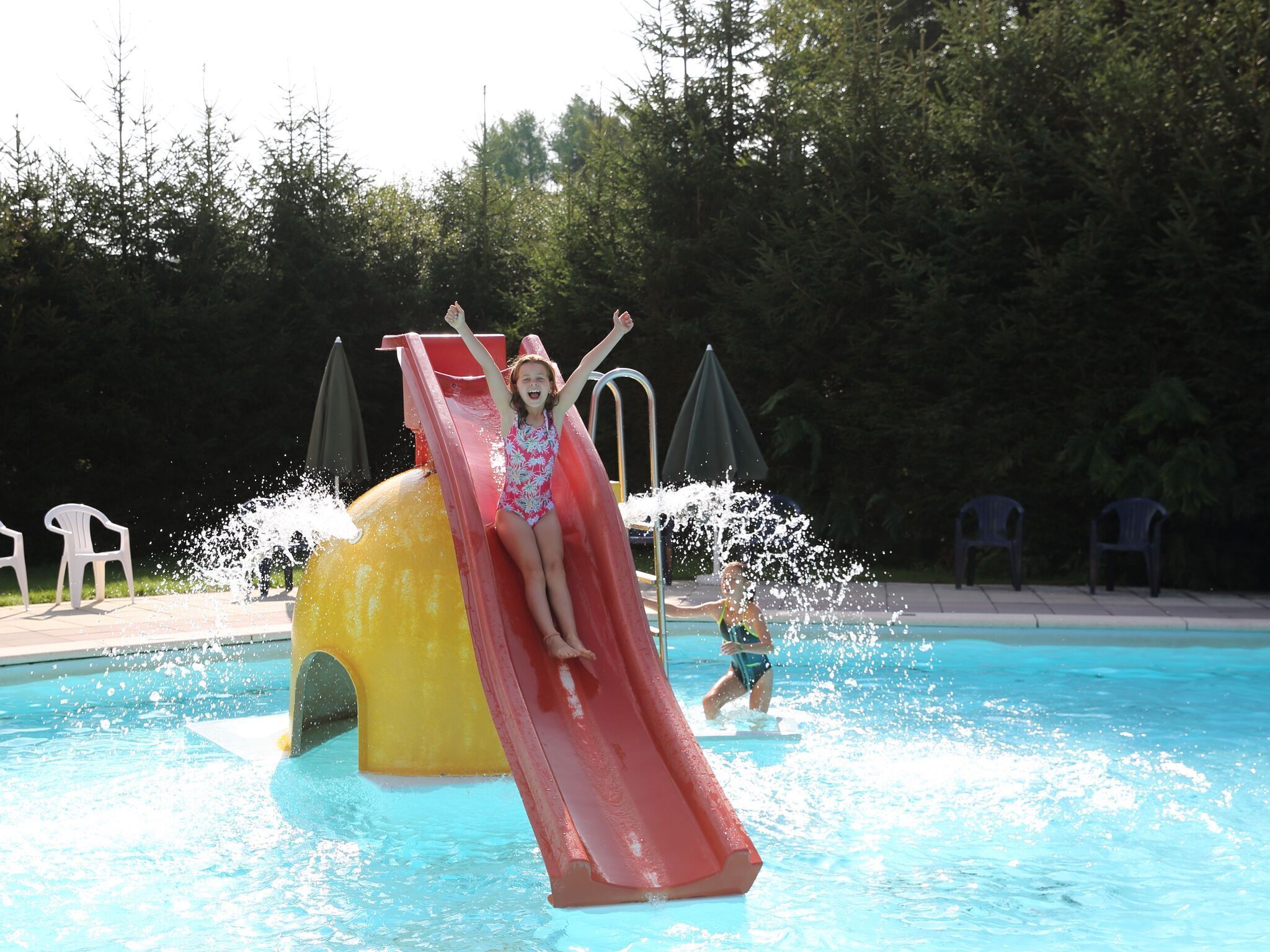 Un toboggan aquatique dans une piscine, avec un enfant qui dévale le toboggan.