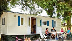 Una casa móvil con porche, una mesa de comedor y sillas.