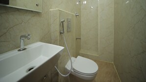 Un baño moderno con un lavamanos blanco, un inodoro y una ducha con cerramiento de vidrio.