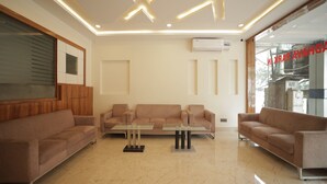 Una sala de estar moderna con una mesa de centro de vidrio, sofás color beige y un piso de mármol.
