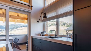 Une cuisine moderne dotée d’une grande fenêtre, d’un plancher en bois et offrant une vue sur la campagne.
