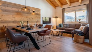 Un salon moderne avec un plafond en bois, un coin repas doté d’une table en bois et un canapé offrant une vue sur l’extérieur.