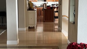 Un pasillo amplio que conduce a una cocina con armarios de madera y una isla central.