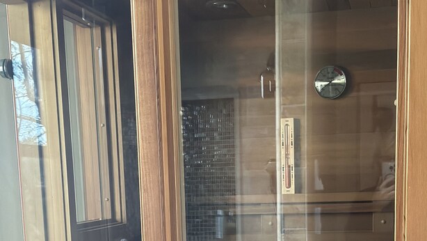 Ventana de madera con vista a una cocina, que incluye armarios y un reloj.