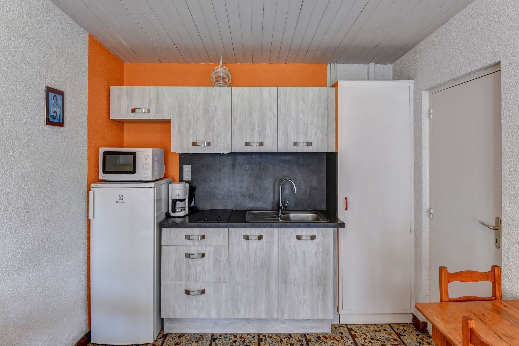 A compact kitchen with a microwave, coffee maker, and sink.