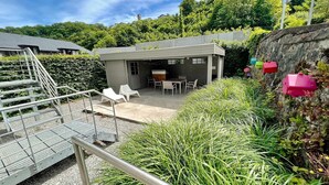 Un espace extérieur moderne, aménagé en patio, avec un coin salon et un escalier menant à un niveau supérieur.