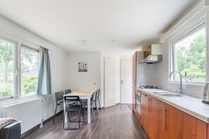 Cucina compatta con zona pranzo, ampie finestre e vista sul verde.