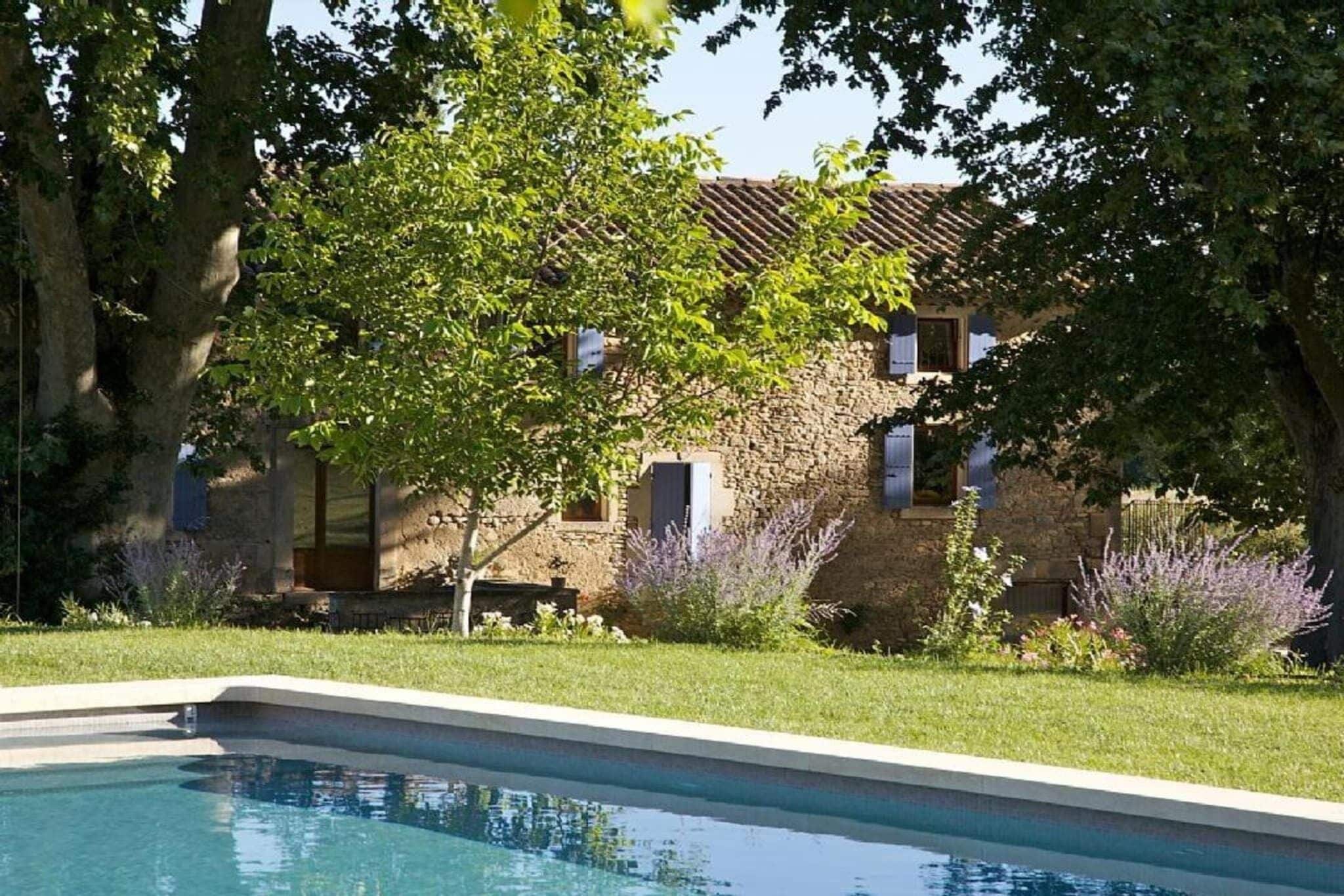 A stone building with a swimming pool in the foreground.