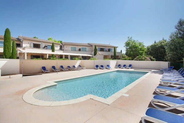 A swimming pool with lounge chairs and a building in the background.