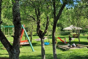 Un parque infantil con columpios, toboganes y un pequeño refugio.