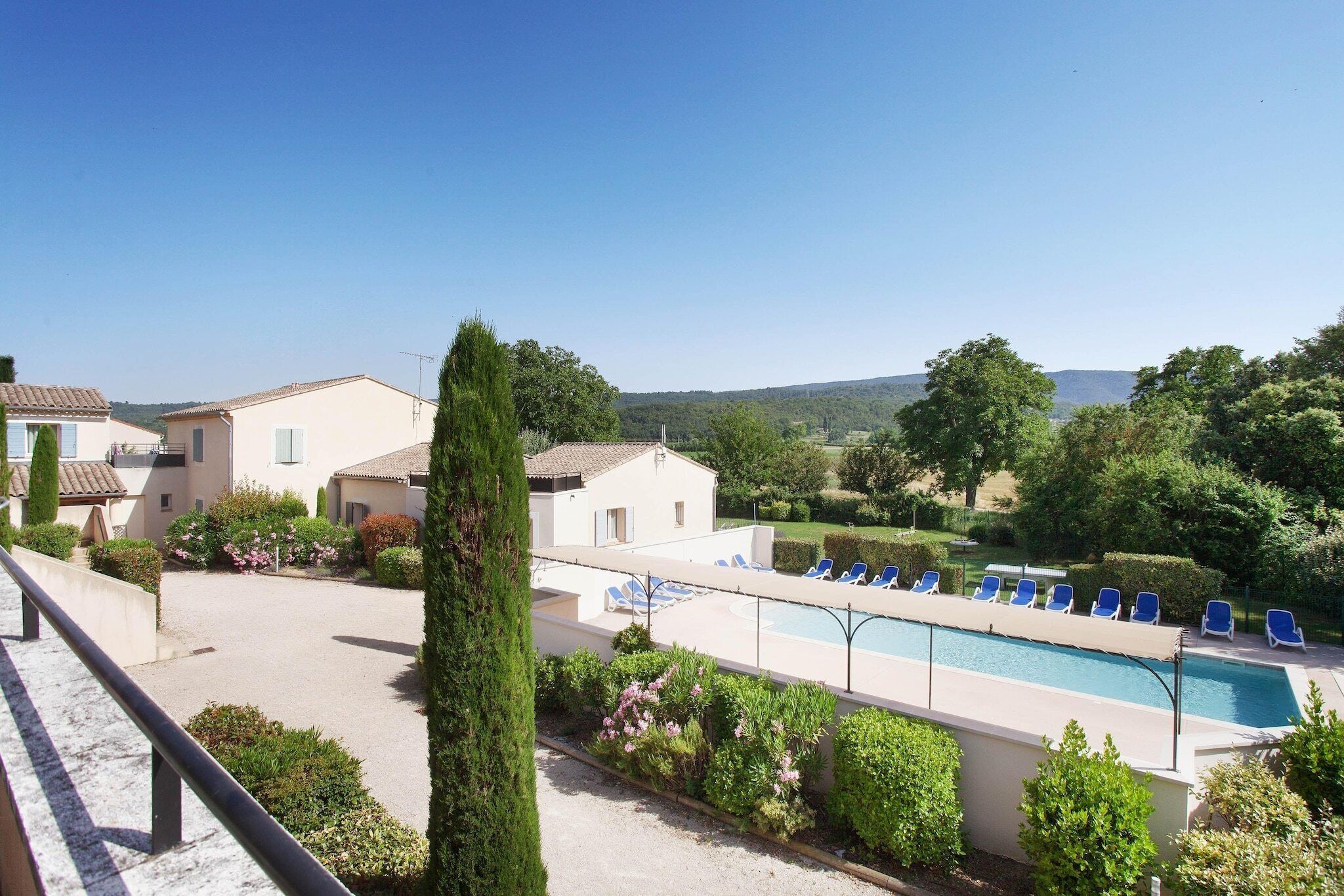 Un espace piscine avec des chaises longues, un ciel dégagé et une végétation luxuriante tout autour.