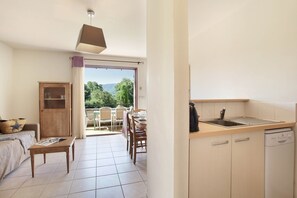 A compact kitchen with a dining area, a wooden cabinet, and a view through the door. - Apartment in Bonnieux near Lavender Fields (BONNIEUX)