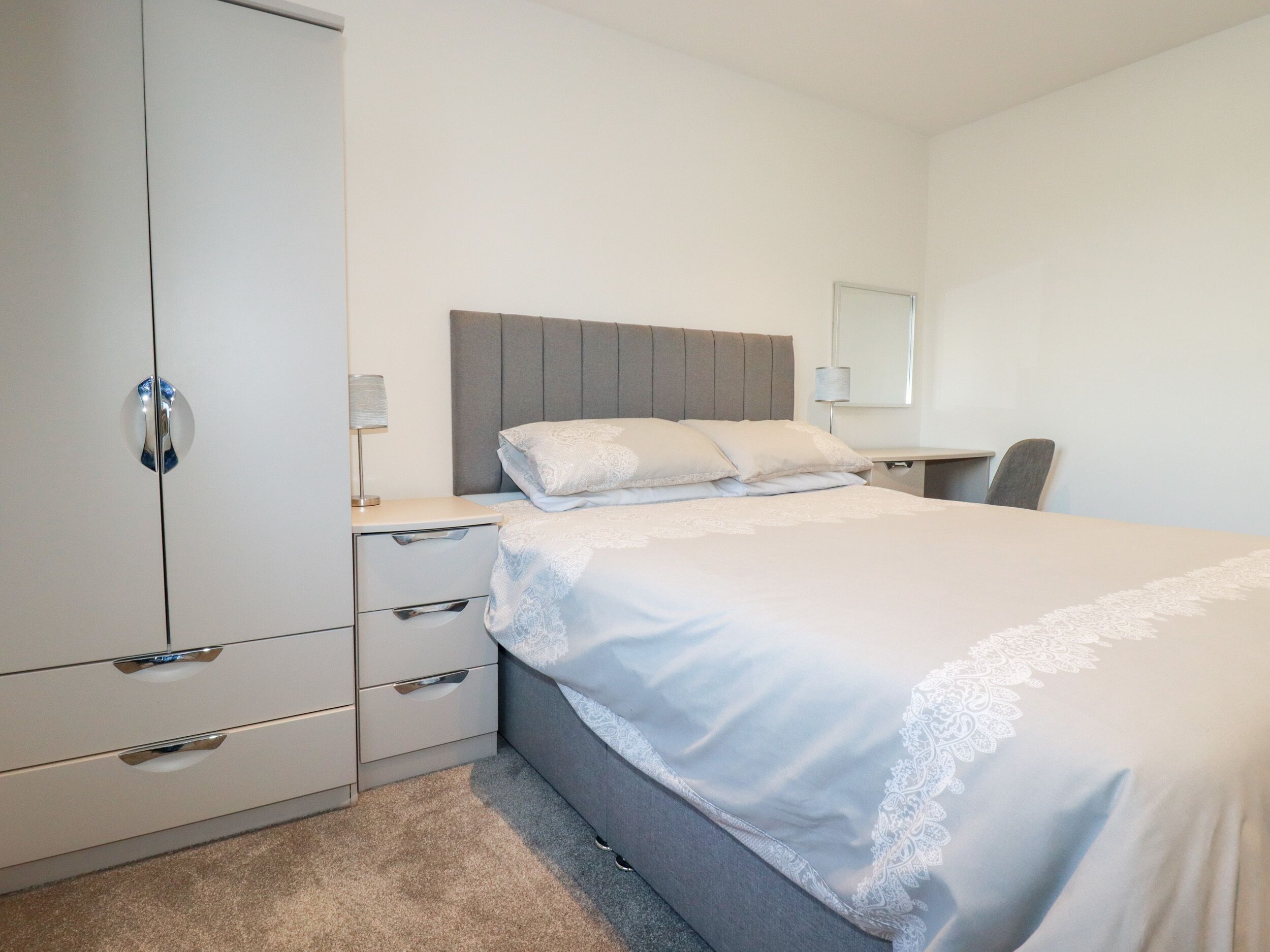 Ein Schlafzimmer mit Bett, Kleiderschrank, Schreibtisch und Stuhl.