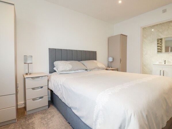 A neatly arranged bedroom with a bed, bedside tables, a wardrobe, and a mirror.