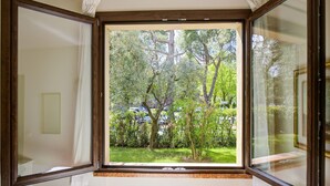 A room with a large window overlooking a garden and parked cars.