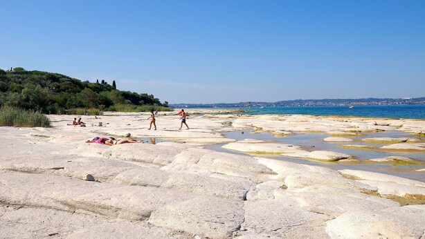 A rocky beach with people sunbathing and swimming.