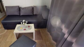 Una sala de estar con un sofá de cuero oscuro, una mesita blanca con una bandeja decorativa y un otoman gris.