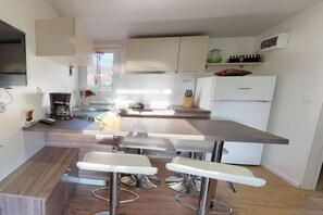 A modern kitchen with a central island, bar stools, and a refrigerator.