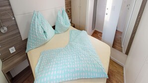 Un dormitorio con cama, dos almohadas, una mesita de noche y un armario.
