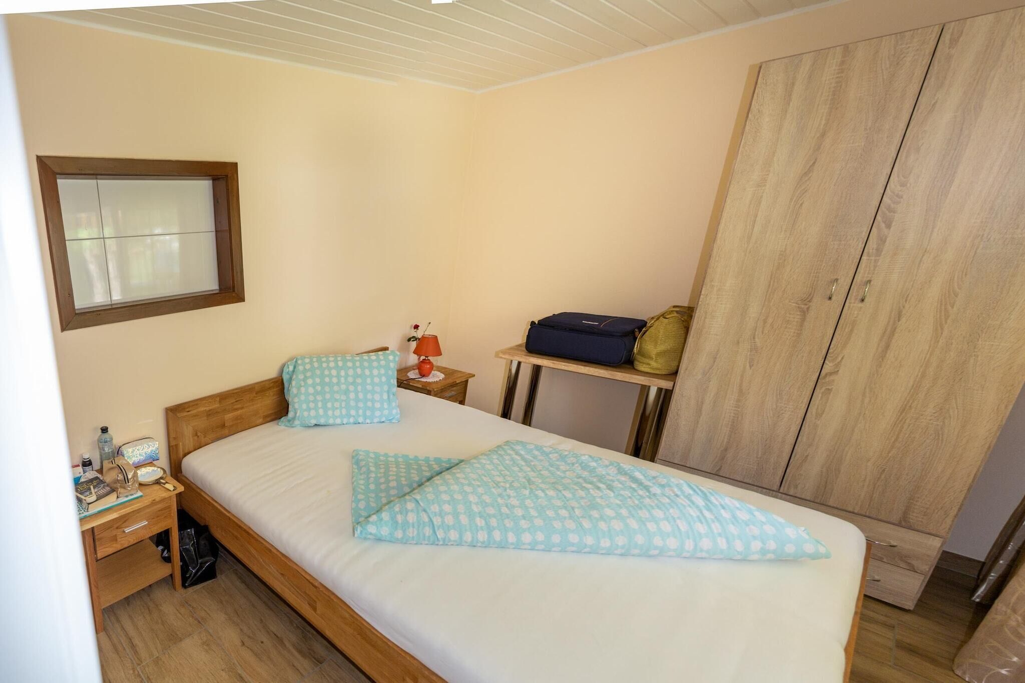 A bedroom with a bed, a nightstand, a wardrobe, and a window.