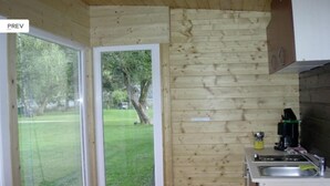 Una habitación con paneles de madera y un ventanal corredero que da a un jardín con césped.