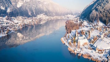 Een winterlandschap met een rivier, besneeuwde gebouwen en bergen.