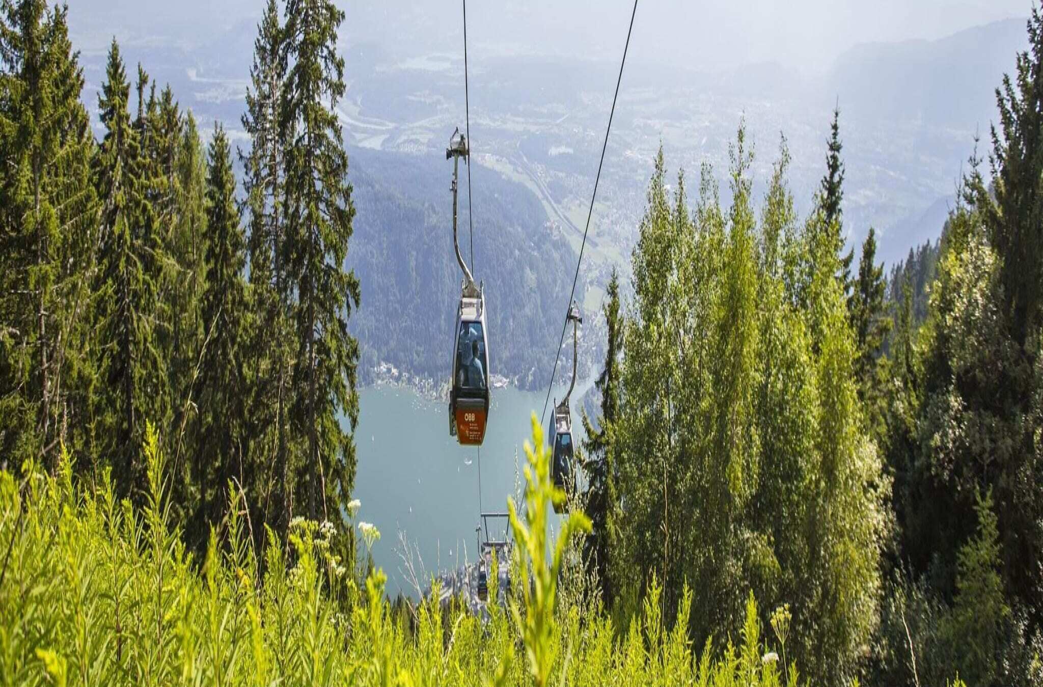 Un sistema de teleférico con un paisaje montañoso y un lago al fondo.