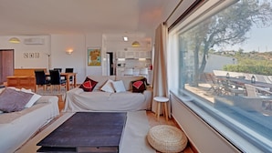 Ein modernes Wohnzimmer mit einer Couch, einem Esstisch und einem durch eine offene Tür einsehbaren Küchenbereich.