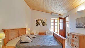 Ein Schlafzimmer mit einem hölzernen Bett, Nachttischen, einem Schminktisch und einer Tür zu einem anderen Raum.