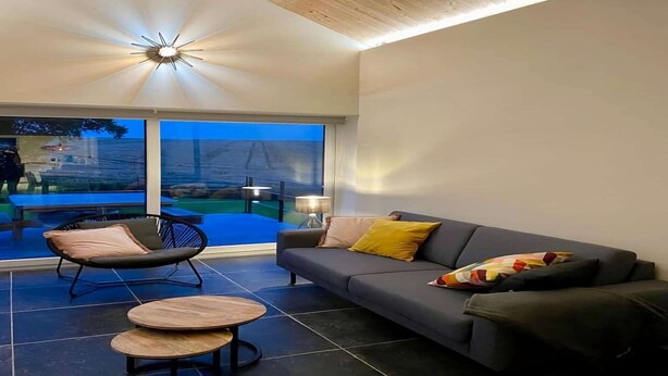 A modern living room with a grey sofa, a black chair, and a small round table. - Peaceful Garden Home in Modave (Modave)