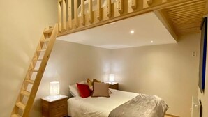 A bedroom with a bed, bedside lamps, a wooden ladder, and a ceiling fan. - Peaceful Garden Home in Modave (Modave)