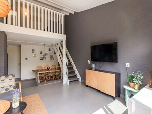Ein modernes Wohnzimmer mit Treppe, Essbereich und einem an der Wand befestigten Flachbildfernseher.
