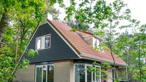 A two-story house with a dark roof, large windows, and a brick exterior. - Holiday Home in Lemele near Nature Reserve (Overijssel)
