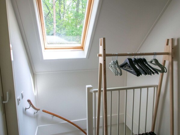 A room with a skylight, a wooden coat rack, and a white door.