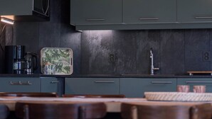 A modern kitchen with dark cabinets, a coffee maker, and a patterned tray. - Holiday Home in Lemele near Nature Reserve (Overijssel)