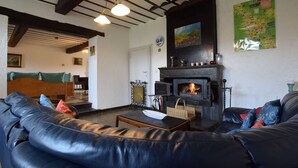 A cozy living room with a black leather sofa, a fireplace, and a map on the wall. - Luxury Holiday Home with Sauna (Melreux-Hotton)